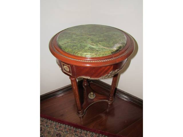 Mesa lateral em madeira de lei, com três pés canelados e aplicações de bronze, além de bela ornamentação por toda a volta da base, encimada por tampo redondo de mármore verde europeu, H = 70 cm e D = 40 cm