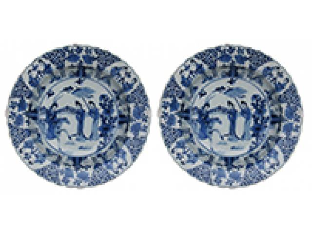 Par de travessas fundas porc. “Cia das Índias”, decor. azul e branco, borda compartimentada e figuras femininas; na caldeira, ilustração variante do celebre motivo da Dame au Parasol, criado por Cornelis Pronck. d = 34 cm. - China. Qing Kangxi (1662-1722)