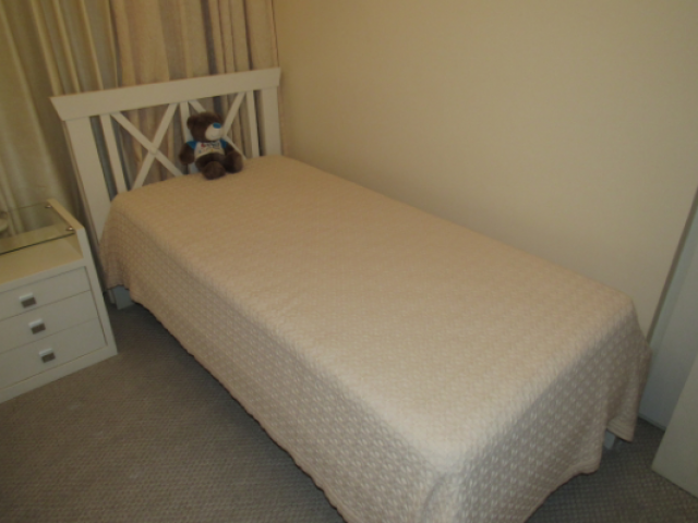 Cama de solteiro branca com espaldar vazado de madeira em forma de "X" acompanha colchão 185 x 85 x 60 cm. (objeto não faz parte deste lote, apenas o móvel)