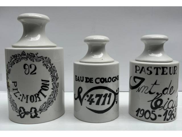 Conjunto com três excepcionais potes de farmácia de porcelana, esmaltagem branca identificadores em negro", medindo 22cmx 17cmx17cm  e assinado Anete datada 1982