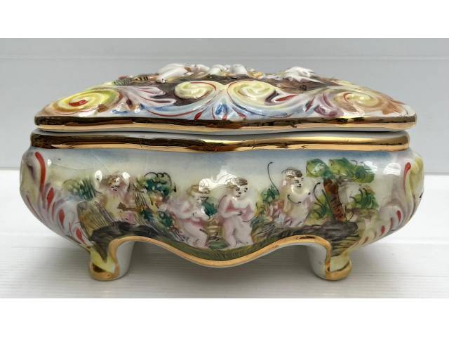Porta joias com tampa basculante em porcelana manufatura Capo Di Monti ornamentada com figura de crianças e querubins em alto relevo. Itália anos 60