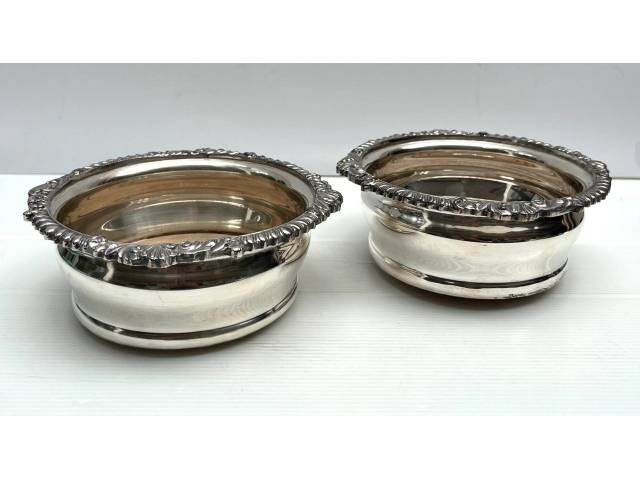 Par de porta garrafa de vinho em metal espessurado a prata, com bordas ornamentadas. Medidas alt. 7 x diam. 17cm